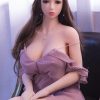 brunette Life Sized Sex Doll in short brown dress sitting on black chair